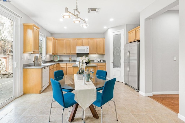 kitchen with sink, hanging light fixtures, light tile patterned floors, light brown cabinets, and white appliances