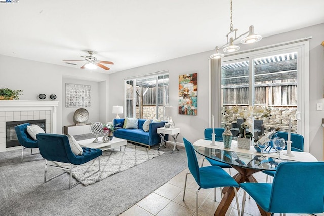 tiled living room featuring ceiling fan, plenty of natural light, and a tiled fireplace