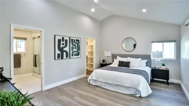 bedroom featuring lofted ceiling, ensuite bath, multiple windows, and light wood-type flooring