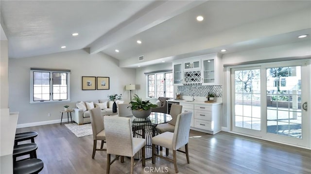 dining room with vaulted ceiling with beams, dark wood-type flooring, and bar area