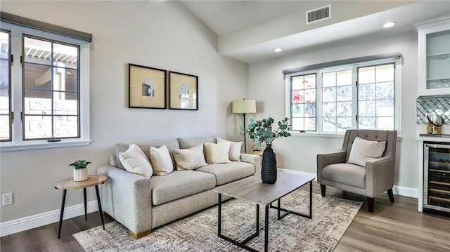 living room with wine cooler, indoor bar, a healthy amount of sunlight, and hardwood / wood-style floors