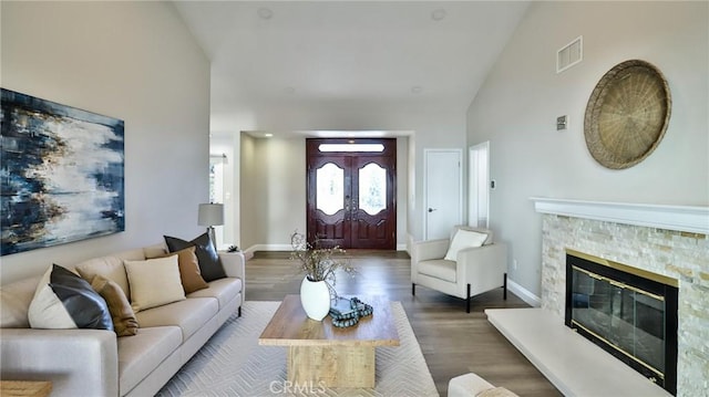 living room with dark hardwood / wood-style flooring, a fireplace, and high vaulted ceiling