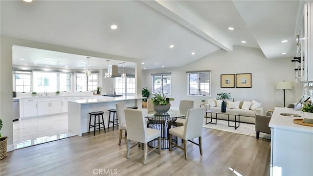 dining area featuring vaulted ceiling with beams and light hardwood / wood-style flooring