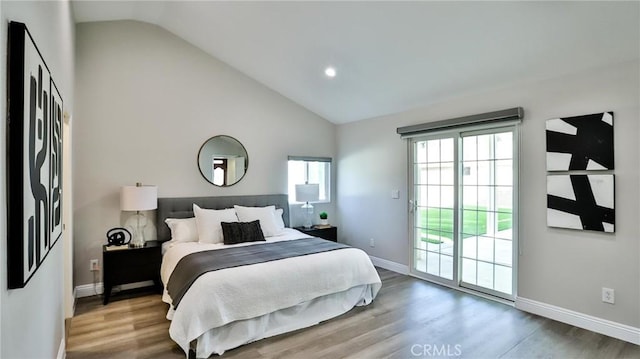 bedroom with hardwood / wood-style floors, access to exterior, and high vaulted ceiling