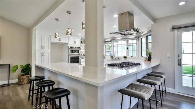 kitchen with a kitchen bar, hanging light fixtures, kitchen peninsula, stainless steel appliances, and white cabinets