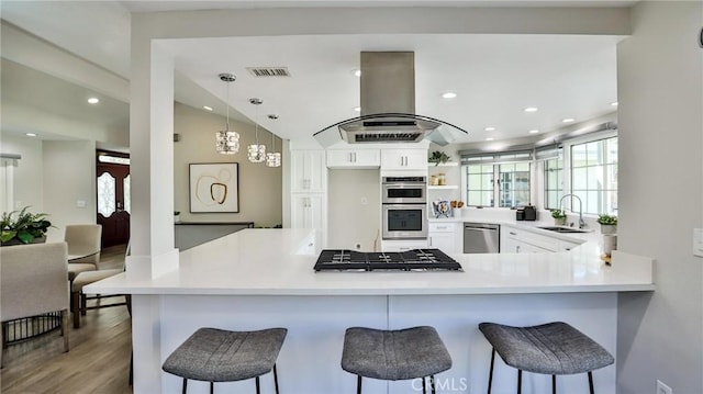 kitchen with sink, white cabinetry, a kitchen breakfast bar, kitchen peninsula, and island exhaust hood