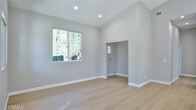 spare room with high vaulted ceiling and light hardwood / wood-style floors