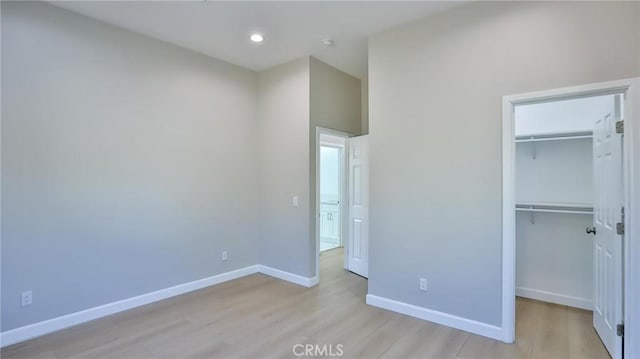 unfurnished bedroom featuring a walk in closet, light hardwood / wood-style floors, and a closet