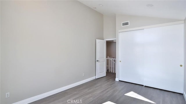 unfurnished bedroom with dark wood-type flooring, high vaulted ceiling, and a closet