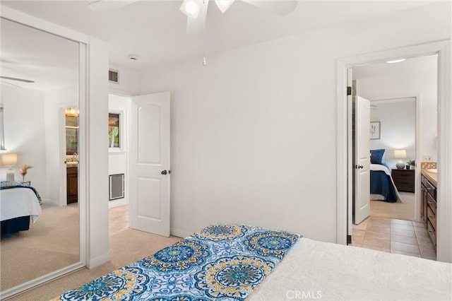 bedroom with ceiling fan, ensuite bathroom, and light colored carpet