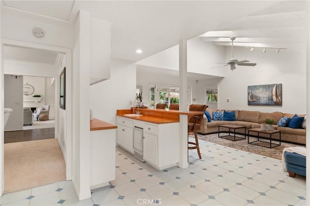 kitchen featuring a kitchen bar, sink, white cabinetry, high vaulted ceiling, and ceiling fan