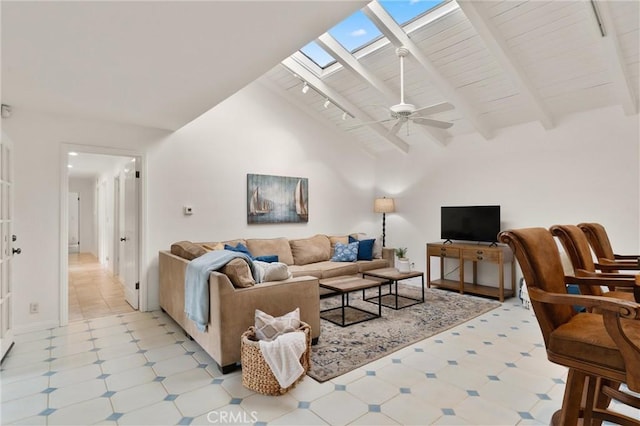 living room with ceiling fan, high vaulted ceiling, beam ceiling, and a skylight