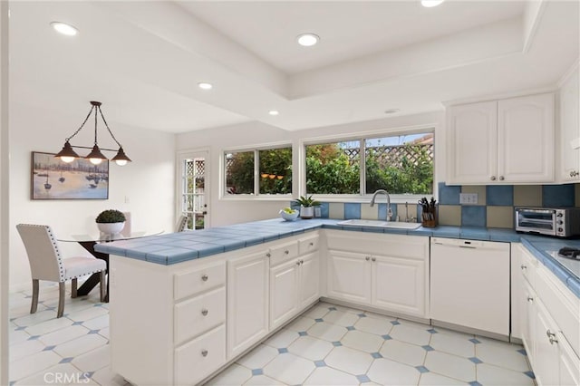 kitchen featuring pendant lighting, sink, white cabinetry, white dishwasher, and a tray ceiling