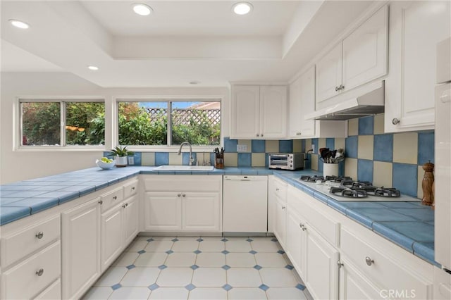 kitchen featuring tile countertops, white cabinetry, sink, a tray ceiling, and white appliances