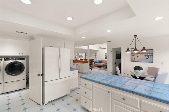 kitchen with white refrigerator, a tray ceiling, tile countertops, and white cabinets