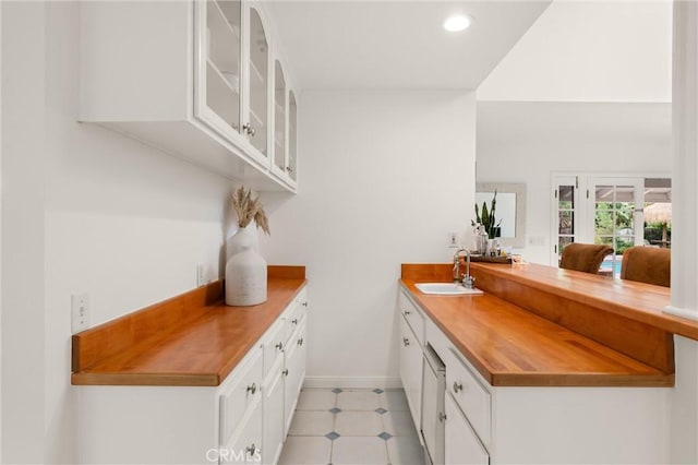 bar featuring butcher block countertops, sink, and white cabinets