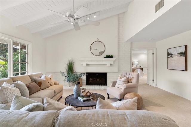 carpeted living room featuring wood ceiling, high vaulted ceiling, a brick fireplace, ceiling fan, and beam ceiling