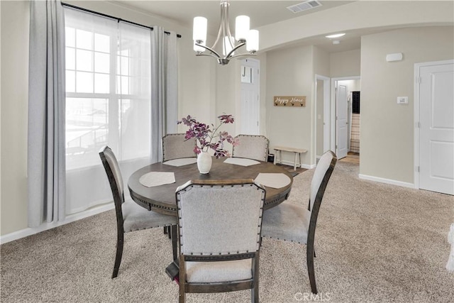 carpeted dining area with a notable chandelier