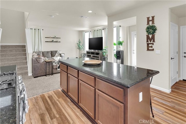 kitchen with dark stone countertops, light hardwood / wood-style floors, and a kitchen island