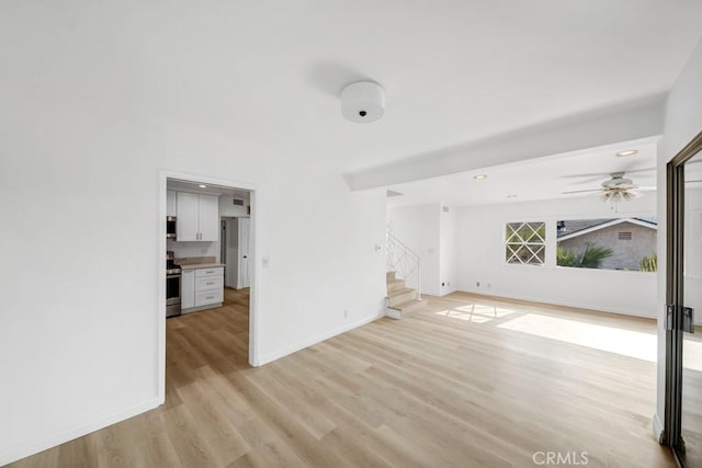 unfurnished living room featuring ceiling fan and light hardwood / wood-style floors