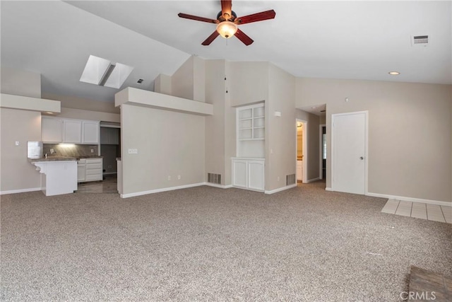 unfurnished living room with a skylight, high vaulted ceiling, ceiling fan, and carpet