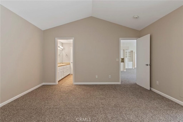 unfurnished bedroom with lofted ceiling, light carpet, and ensuite bathroom