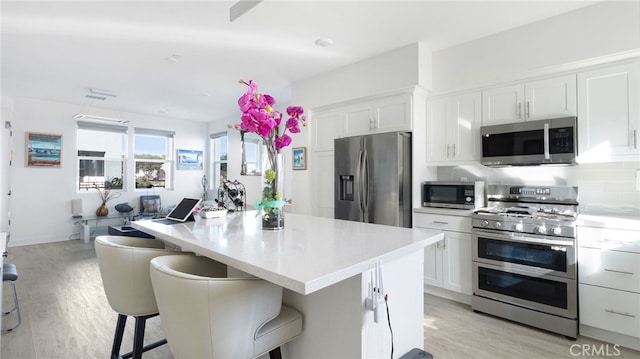 kitchen featuring stainless steel appliances, a breakfast bar, white cabinets, and a center island