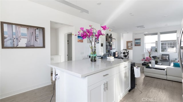 kitchen with white cabinetry, a center island, a breakfast bar area, and light wood-type flooring