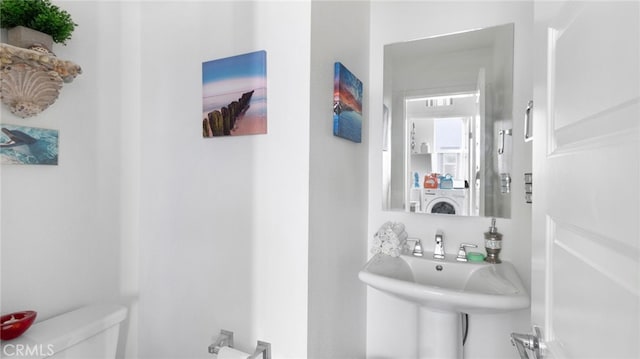 bathroom featuring washer / clothes dryer, sink, and toilet