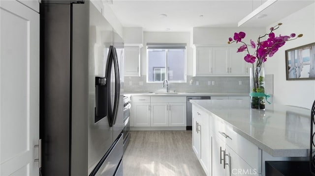 kitchen with white cabinetry, tasteful backsplash, stainless steel appliances, and light hardwood / wood-style flooring