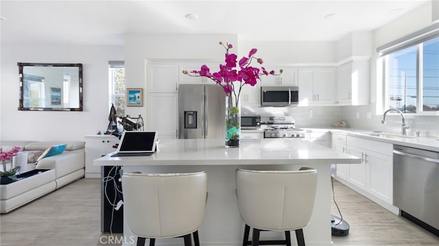 kitchen with a kitchen bar, plenty of natural light, white cabinets, and appliances with stainless steel finishes