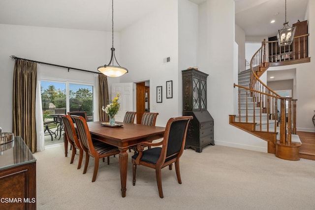 carpeted dining area featuring a towering ceiling