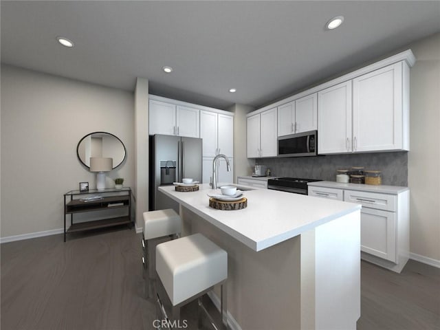 kitchen featuring white cabinetry, stainless steel appliances, a kitchen bar, and an island with sink