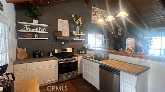 kitchen with sink, dark hardwood / wood-style flooring, stainless steel appliances, beam ceiling, and white cabinets