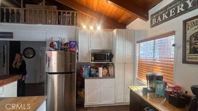 kitchen featuring white cabinetry, wood ceiling, lofted ceiling with beams, and stainless steel appliances