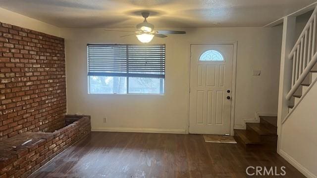 entryway with wood finished floors, ceiling fan, baseboards, and stairs