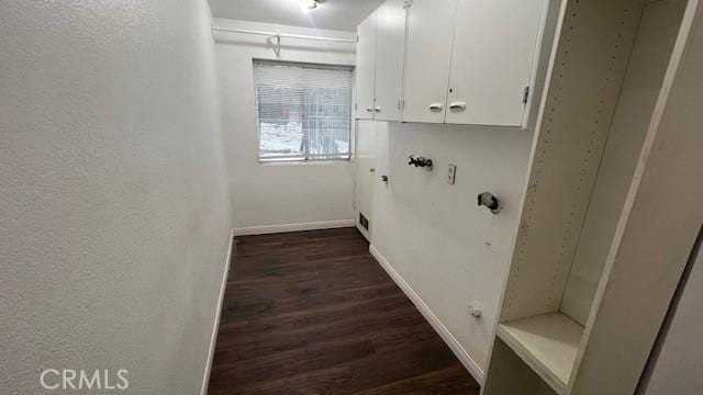 laundry room with cabinet space, baseboards, and dark wood-type flooring