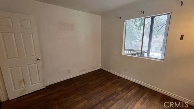 empty room featuring dark wood-style floors and baseboards