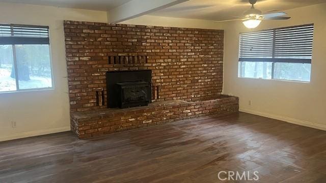 unfurnished living room with wood finished floors, a healthy amount of sunlight, baseboards, and beam ceiling