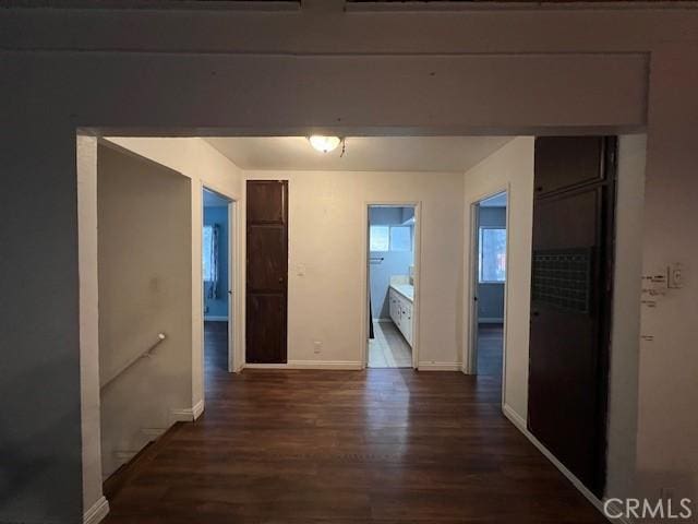 corridor featuring dark wood-style flooring and baseboards