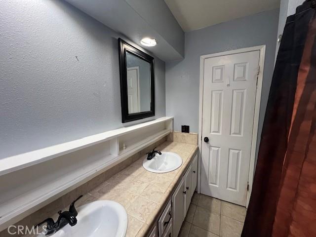 bathroom with double vanity, a sink, and tile patterned floors