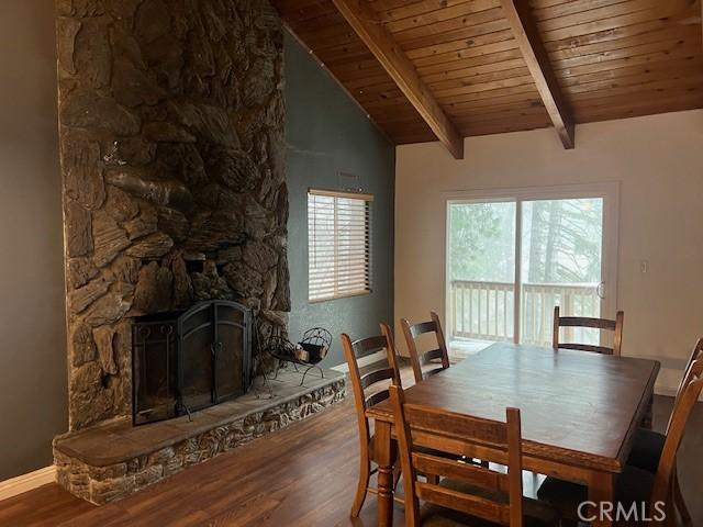dining area with wooden ceiling, a fireplace, vaulted ceiling with beams, baseboards, and wood finished floors