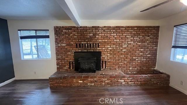 unfurnished living room with wood finished floors, beamed ceiling, and baseboards