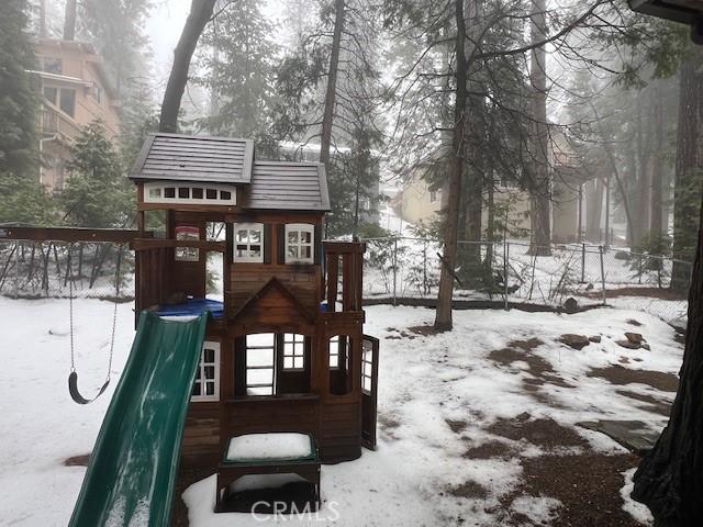 snow covered playground with a playground and fence