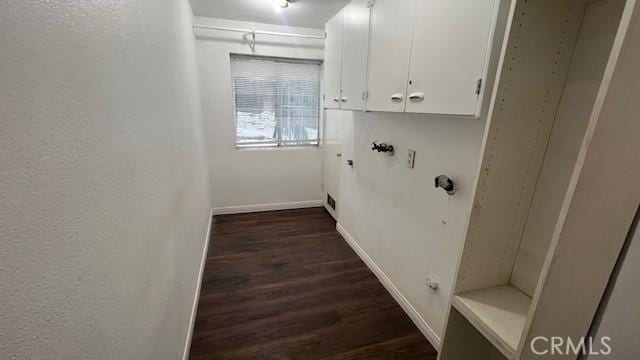 laundry room featuring a textured wall, cabinet space, dark wood finished floors, and baseboards