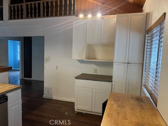 kitchen featuring dark wood-style flooring, wood counters, open shelves, white cabinetry, and lofted ceiling
