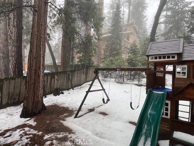 snow covered playground with fence and a playground