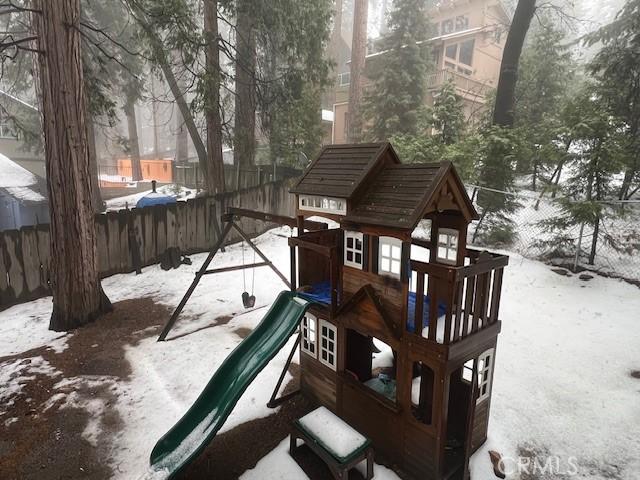 snow covered playground featuring fence and a playground