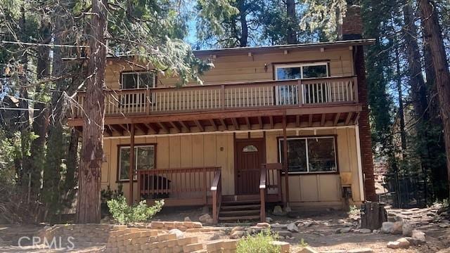 back of property with a chimney and a wooden deck