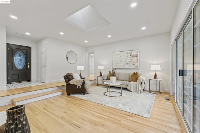 living room with a skylight and light hardwood / wood-style flooring